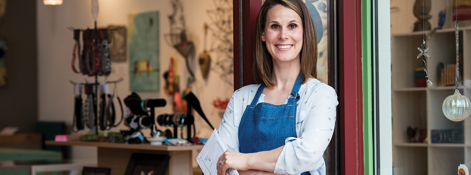 a small business owner stands inside the door of her shop smiling