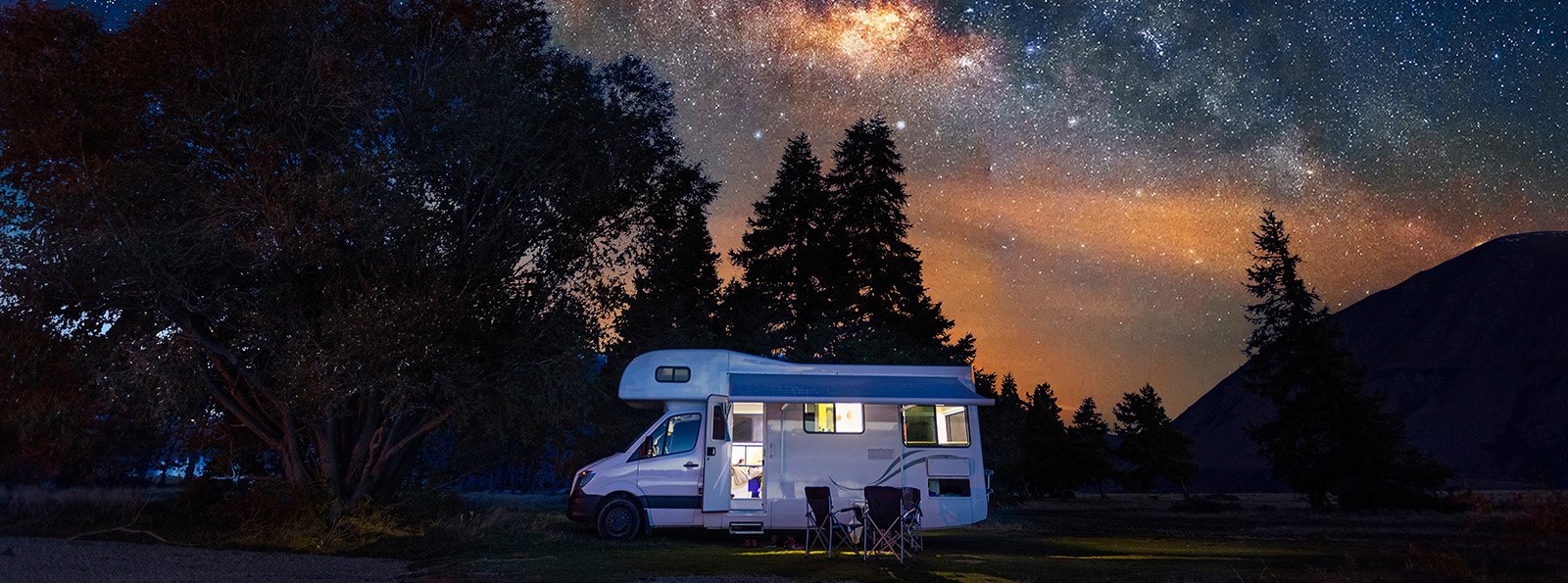 an RV sits under the beautiful stars in a wooded area