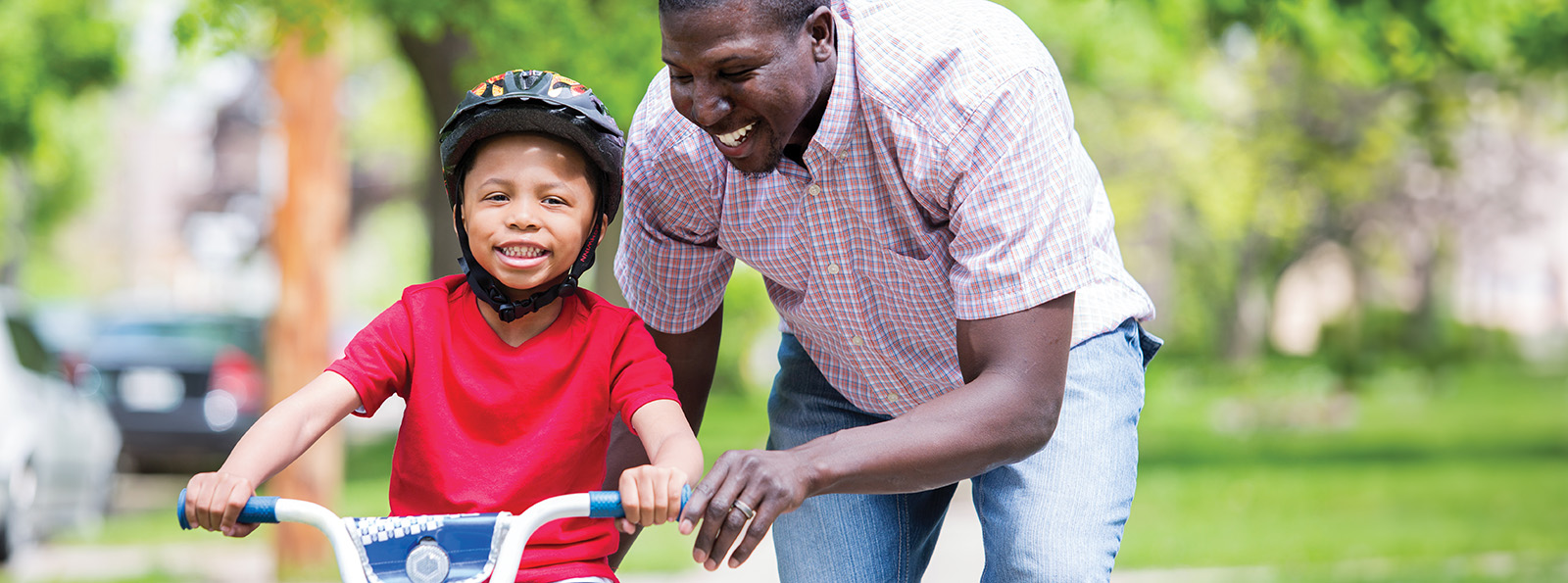 a father helping his young son to learn to ride a bike