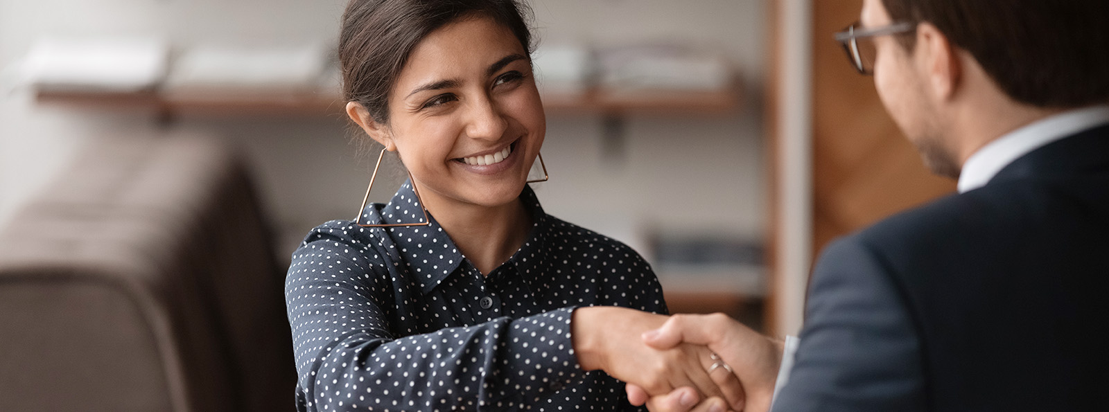 a young woman smiles as she shakes the hand of a young man