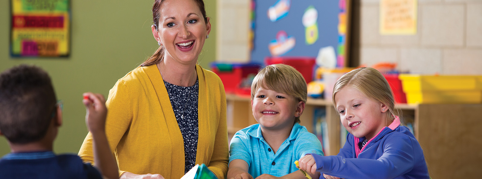 a teacher sits in her classroom with her smiling students