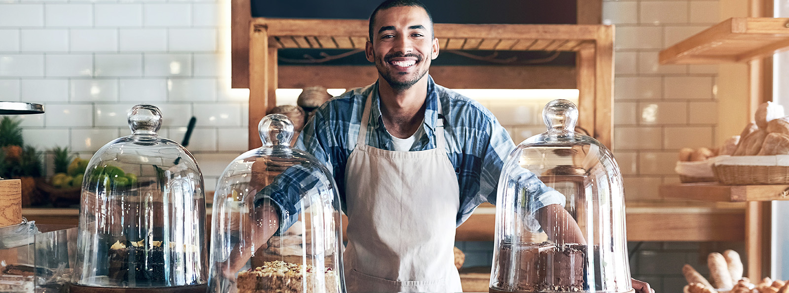 a smiling bakery owner poses in his store amid various baked treats